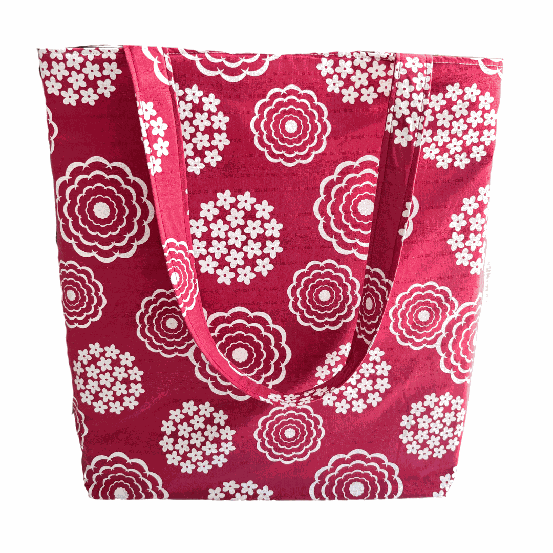 A handprinted cottage garden handmade shoulder bag in white and rouge with a floral pattern on a red background.
