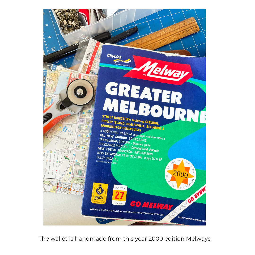 Melway Greater Melbourne street directory on a table with maps and tools