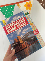 Vintage Australian Road Atlas held by a hand on a white background