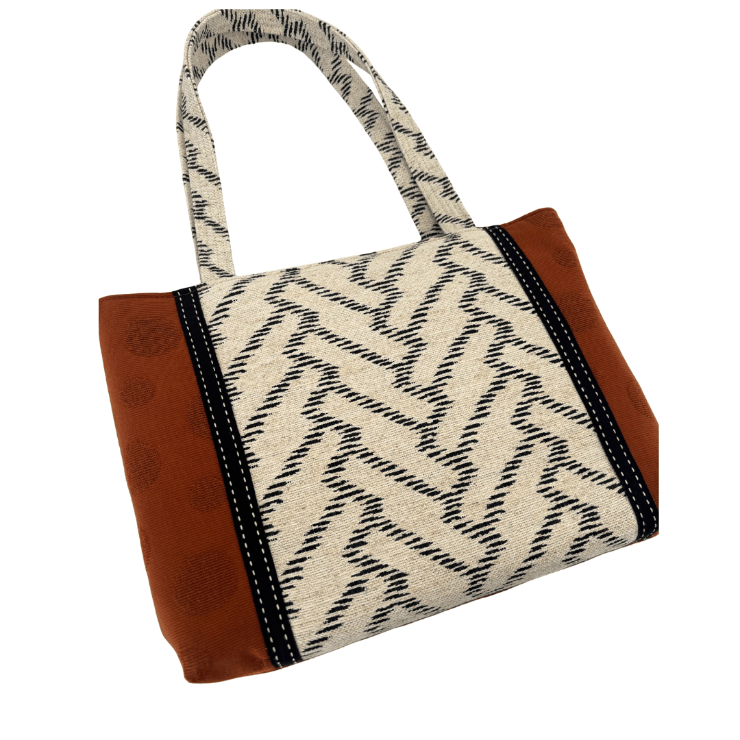 Front view of Burnt Caramel Noir handcrafted shoulder bag on white background showing structured silhouette and woven chevron handles – Lyssy May