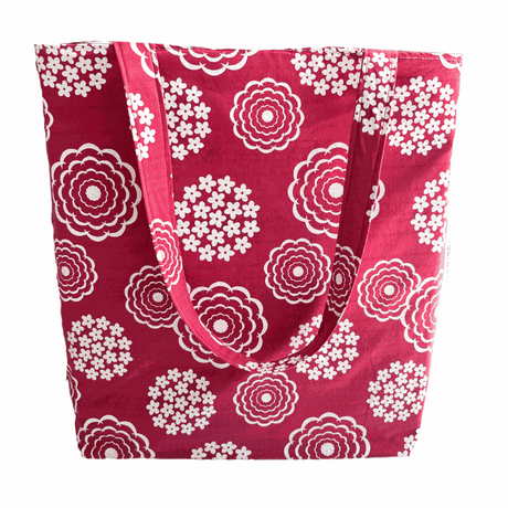 A handprinted cottage garden handmade shoulder bag in white and rouge with a floral pattern on a red background.