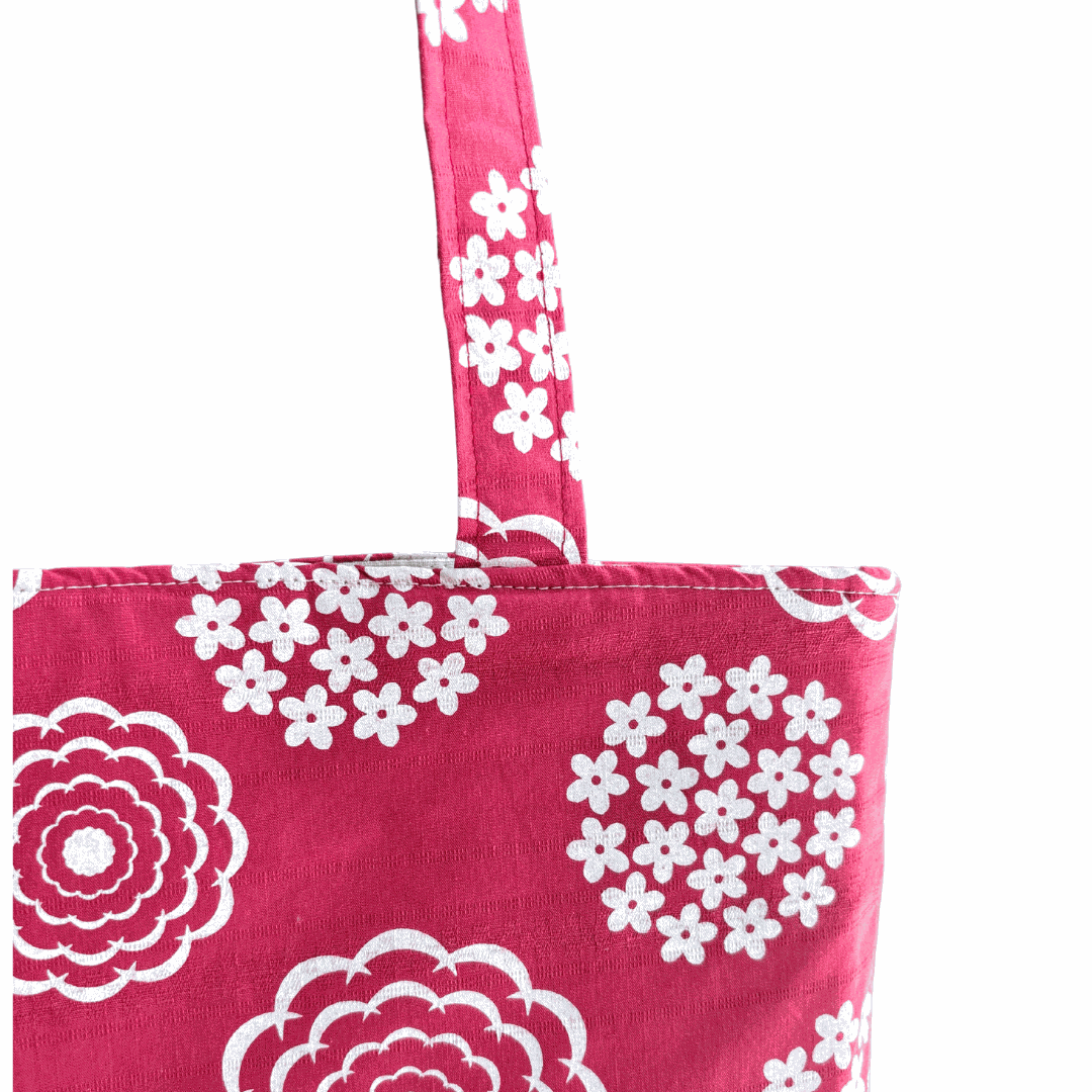 LyssyMay handnprinted tote bag with white floral patterns on a white background. handle detail