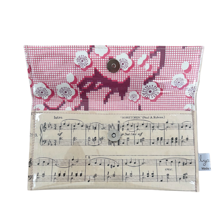 Small pouch with floral pattern on top and sheet music design on the bottom, on a white background.