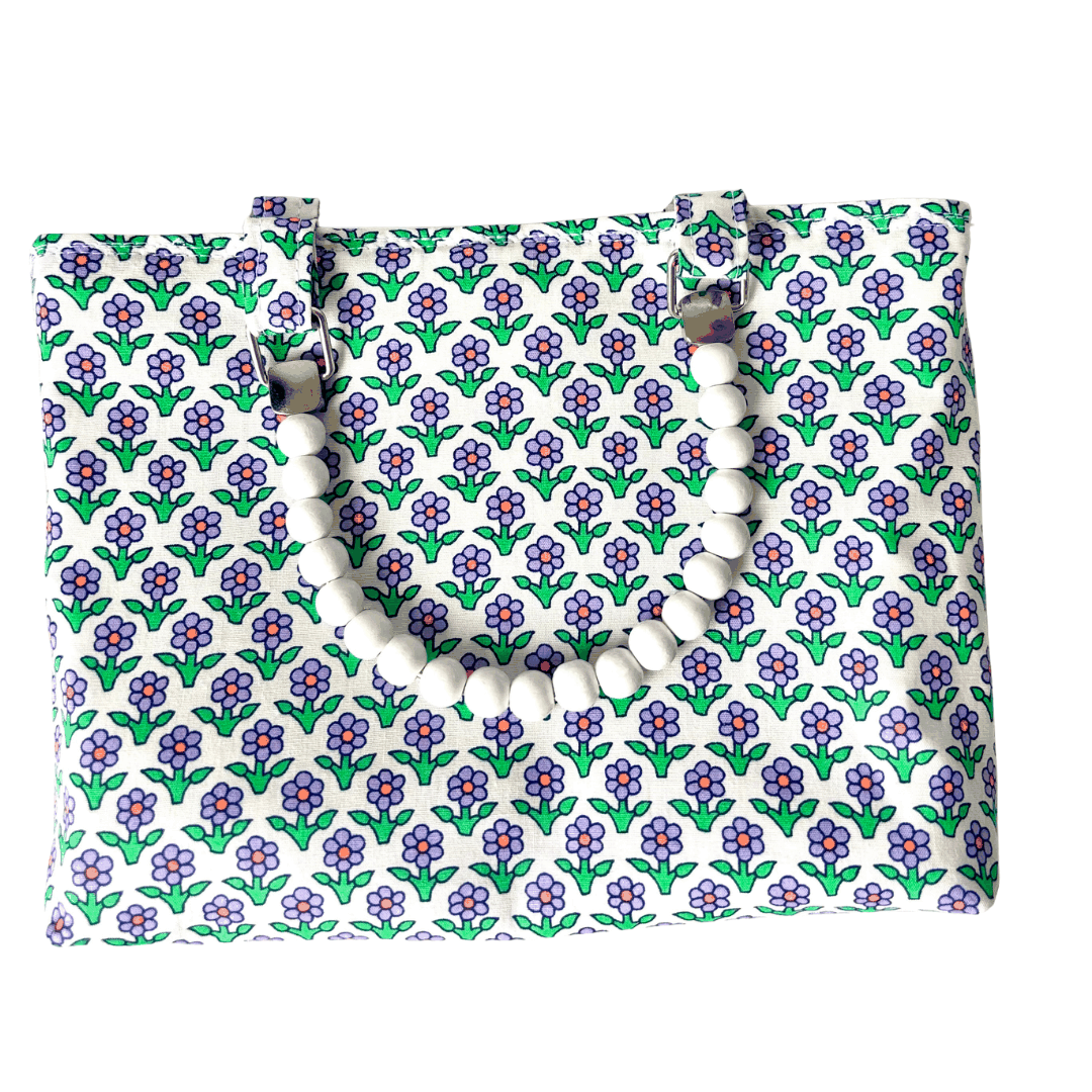 Floral patterned bag with a white beaded handle on a white background