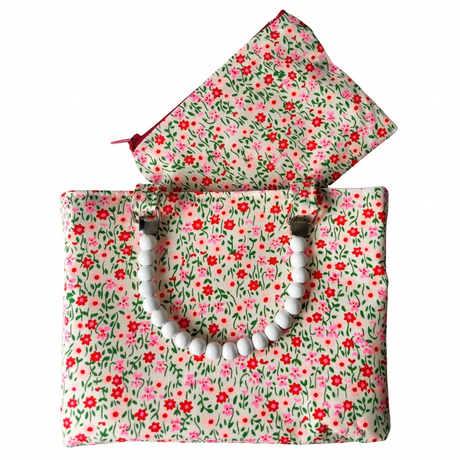 Floral-patterned handmade bag with a white beaded handle on a white background