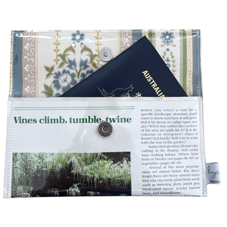 Floral-patterned handmade wallet which fits a passport, featuring text and images on the cover.