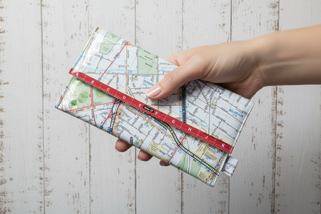 Hand holding a map-patterned wallet for scale